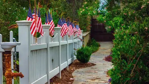 Row of American flags on white picket fence for garden decor