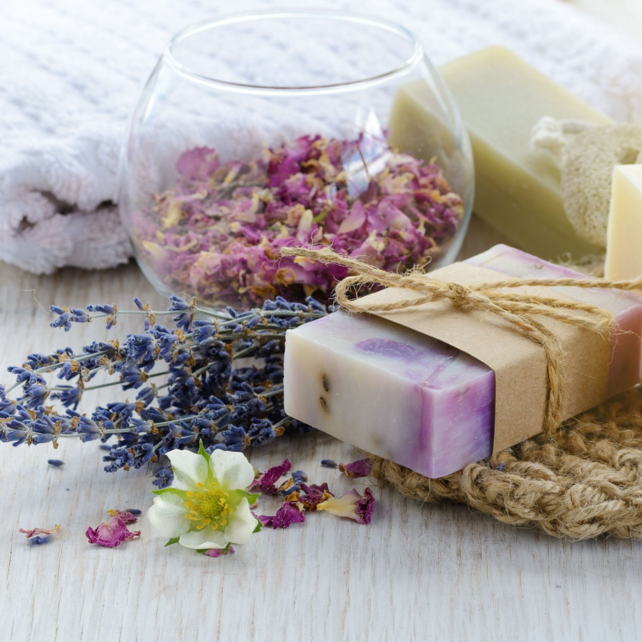Handmade soap bars with lavender and rose petals on a wooden surface